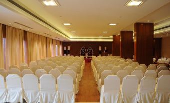 a large conference room with rows of white chairs and a stage at the front at Moti Mahal