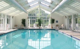 a large swimming pool with a glass ceiling and white lounge chairs is surrounded by windows at The Martha Washington Inn and Spa
