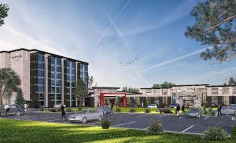 a modern building with a red archway and cars parked in front , under a clear blue sky at Courtyard Oshawa