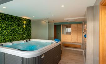 a large , rectangular hot tub with a wooden floor and walls decorated with greenery , next to a shower area at Golden Star City Resort