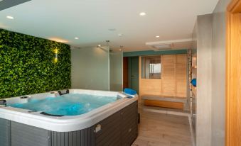 a large , rectangular hot tub with a wooden floor and walls decorated with greenery , next to a shower area at Golden Star City Resort