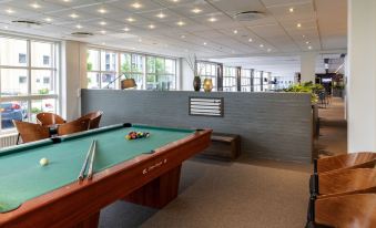 a room with a green pool table surrounded by chairs and couches , creating a comfortable space for playing at Pier 5 Hotel