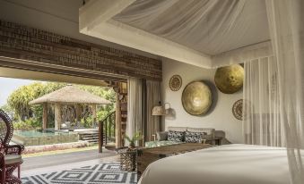 a luxurious bedroom with a large bed , a bathroom , and a patio area with a gazebo at Four Seasons Resort Seychelles at Desroches Island