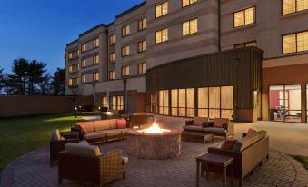 a large outdoor patio area with a fire pit , couches , and chairs surrounded by buildings at Courtyard Burlington Mt. Holly/Westampton