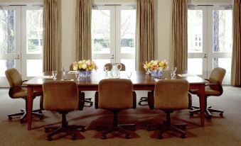 a conference room with a large wooden table surrounded by chairs , and a window in the background at Southbridge Napa Valley