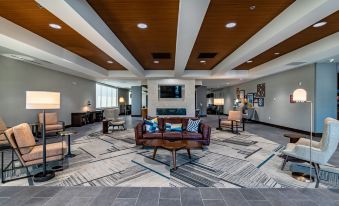 a modern hotel lobby with a large flat - screen tv mounted on the wall , a couch , and several chairs arranged around it at Four Points by Sheraton Brunswick