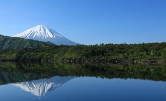 a serene scene of a lake with snow - capped mountains in the background , creating a picturesque landscape at HOTEL MYSTAYS Fuji Onsen Resort