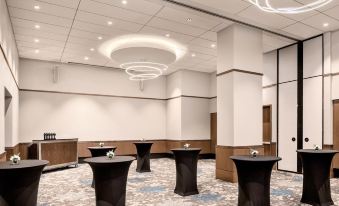 a large conference room with multiple tables and chairs , illuminated by lights on the ceiling at The Civic Hotel