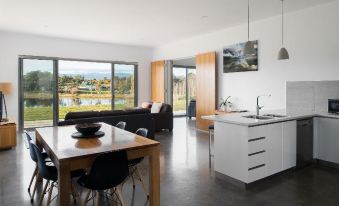 a modern living room and kitchen area with a large window , wooden furniture , and a black couch at Relbia Lodge