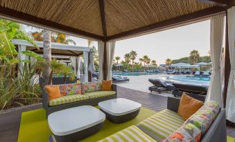 a poolside lounge area with several couches and chairs , creating a comfortable seating area for guests at Conrad Algarve