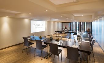 a conference room with several chairs arranged in rows and a projector screen mounted on the wall at Conrad Bora Bora Nui