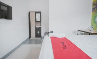 a white bedroom with a bed and a red blanket , next to a black door at RedDoorz @ Beringin Jambi