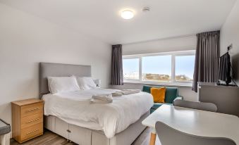 a modern hotel room with a large bed , white bedding , and a view of the ocean at North Devon Resort