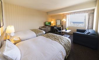 a hotel room with two beds , a television , and a window overlooking a cityscape at Hotel Aomori