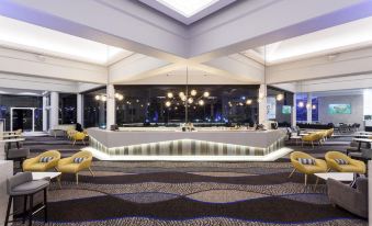 a modern hotel lobby with a large reception desk , multiple chairs , and a high ceiling at Sea World Resort