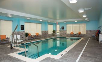 an indoor swimming pool with a blue and white tiled floor , surrounded by chairs and tables at Homewood Suites by Hilton Allentown Bethlehem Center Valley