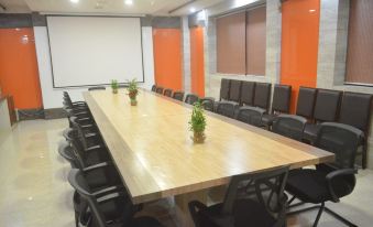 a long wooden conference table with multiple chairs arranged around it , surrounded by an orange room at Leisure Resort
