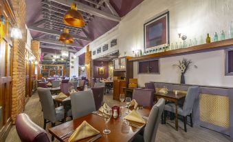 a restaurant with tables and chairs , a chandelier , and various decorations on the walls at The Forest Lodge