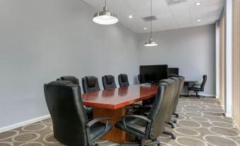 a conference room with a long wooden table surrounded by black leather chairs and a large screen tv at Quality Inn & Suites Conference Center