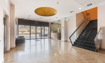 a modern office lobby with a reception desk , large windows , and a staircase leading to the upper level at Fuente del Miro