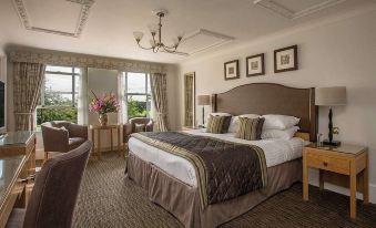 a large bed with a wooden headboard is in the middle of a room with framed pictures on the wall at Rookery Hall Hotel & Spa