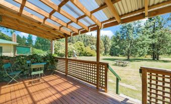 a wooden deck with a pergola , covered patio area , and a view of a park at Giants Table and Cottages