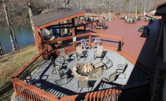 a large deck with a fire pit surrounded by chairs , overlooking a body of water at Skyline Lodge