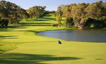 a beautiful golf course with lush green grass , trees , and a lake in the background at Joondalup Resort