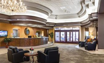 a hotel lobby with a large reception desk , several chairs , and a chandelier hanging from the ceiling at Grand Hotel