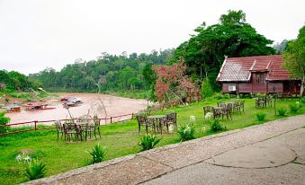 a serene outdoor setting with a wooden house surrounded by lush greenery , including trees and bushes at Mutiara Taman Negara