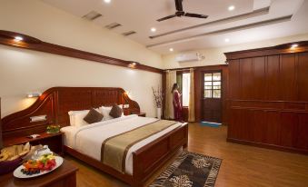 a spacious bedroom with a king - sized bed , hardwood floors , and a woman standing in the doorway at Coorg Cliffs Resort