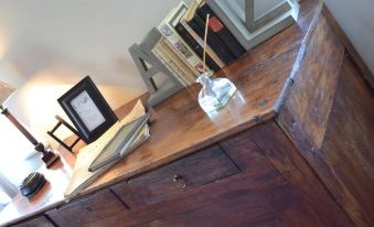 a wooden desk with various items on it , including a clock , a picture frame , and a vase at Le Petit Chou