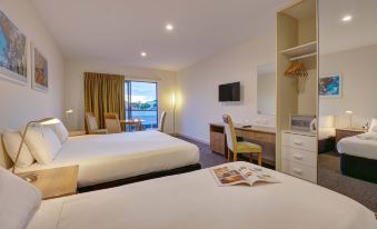 a hotel room with two beds , a desk , and a window , all decorated in white and gold colors at Aurora Ozone Hotel Kangaroo Island