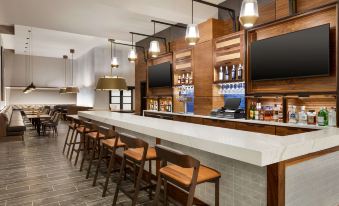 a modern bar with wooden walls , white marble countertops , and several chairs surrounding it , as well as various liquor bottles on display at Doubletree by Hilton Columbus Dublin
