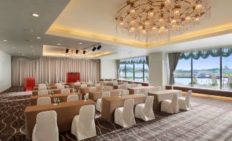 a large conference room with rows of chairs arranged in a semicircle , and a chandelier hanging from the ceiling at Loisir Hotel Naha