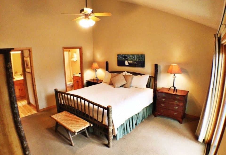 a large bed with a wooden headboard and footboard is in the center of a room with two lamps on either side at Mountain Lake Lodge