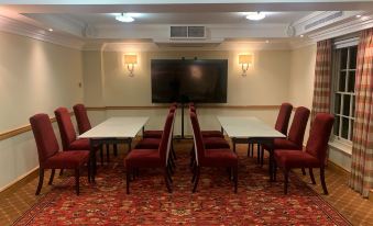 a room with a long table and chairs , a television on the wall , and lamps on the ceiling at The Woburn