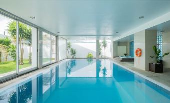 a large , empty indoor swimming pool with a white ceiling and walls , surrounded by windows and modern interior design at Hotel Vale Do Navio