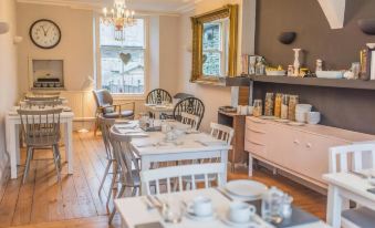 a dining room with white chairs and tables , along with a kitchen in the background at Chestnut Villa