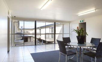 a modern office building with large windows , a dining table and chairs , and a potted plant at Mandarin Motel