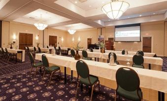 a large conference room with multiple rows of chairs arranged in a semicircle , and a projector screen on the wall at UMass Lowell Inn and Conference Center