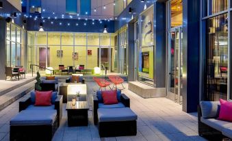 an outdoor seating area of a building , with several chairs and couches arranged for patrons to enjoy the space at Aloft Chesapeake