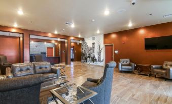 a spacious lobby with wooden floors , large windows , and comfortable seating arrangements , including a couch and coffee table at Cobblestone Hotel & Suites - Two Rivers