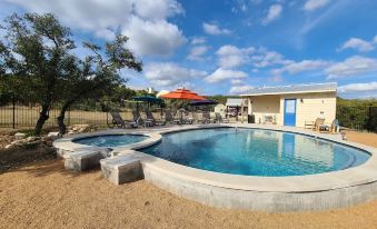 a large swimming pool with a patio and lounge chairs is surrounded by a building at Hill Country Casitas