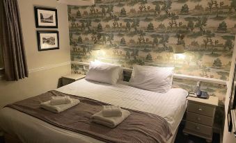 a neatly made bed with white sheets and towels is shown in a hotel room at The Bridge Inn