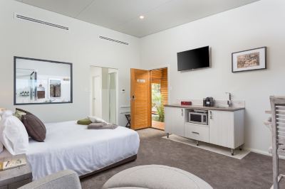 a clean and well - organized hotel room with a comfortable bed , a television , and a kitchenette at The Swan Valley Retreat