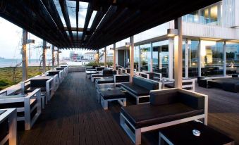 a long wooden deck with several couches and chairs arranged for outdoor dining , creating a comfortable seating area at Altis Belem Hotel & Spa, a Member of Design Hotels