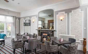 a dining room with a fireplace , several chairs , and a television mounted on the wall at The Valley of Rocks Hotel