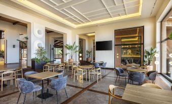 a modern lounge area with wooden tables and chairs , a television on the wall , and plants at Barceló Tenerife