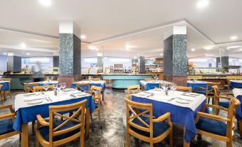 a large dining room with multiple tables and chairs , some of which are covered in blue tablecloths at Vik Gran Hotel Costa del Sol